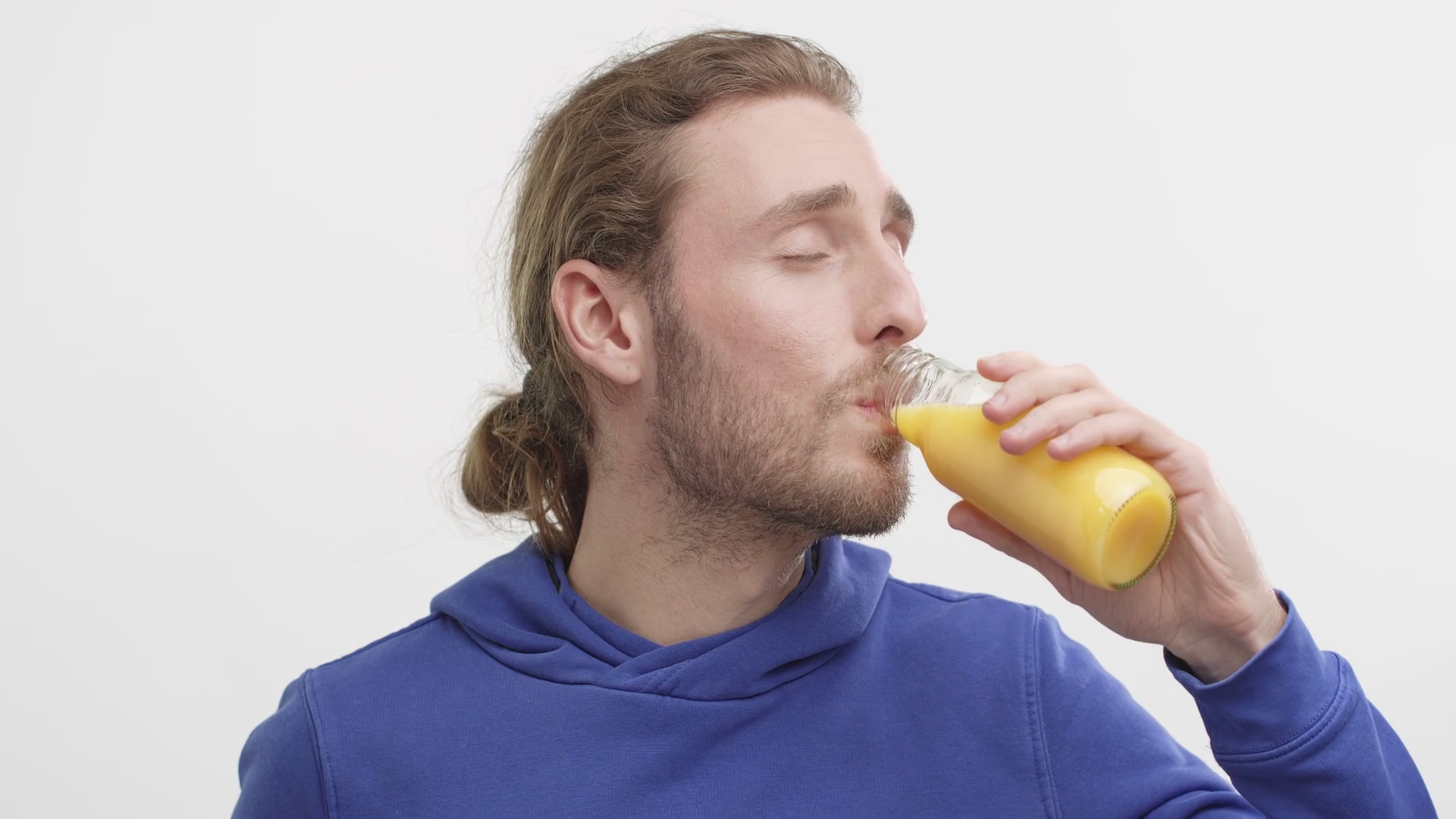 Happy Young Man Enjoy drinking Orange Juice from a Bottle on white