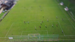 Aerial view of football field with players in rural spring landscape using tilt-shift effect
