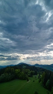 Vertical Hyperlapse of Lush Green Hills with Sun Rays and Moving Clouds in Spring