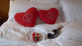 Bottle of champagne sparkling wine and plate with dessert cake at bed.