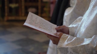 Priest holds gospel book or Bible and reads prayer. Christianity or Catholicism