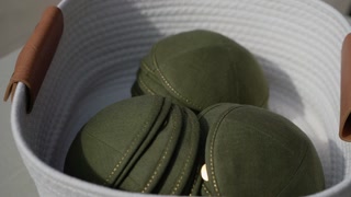 Green Kippah Stacked On Table, CloseUp Of Folded Fabric Cap Next To Patterned Program And Pen, Soft Natural Light, Shallow Depth Of Field,