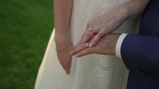 Bride And Groom Hands Exchanging Rings Cinematic Slow Motion Closeup On Gold Band And Fingers, Soft Evening Light Over Garden Lawn, White