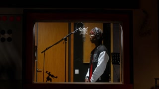 The rapper is recording a song in a recording studio. View through the window from the operator's side