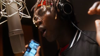 A man with headphones dances when he sings rap. Professional recording Studio