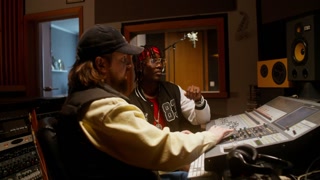Listening to the song after recording in the studio. The sound engineer and the performer are sitting in front of the monitor in the control