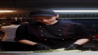 A woman in a chef's uniform with disposable black gloves on her hands cuts cabbage in the restaurant kitchen