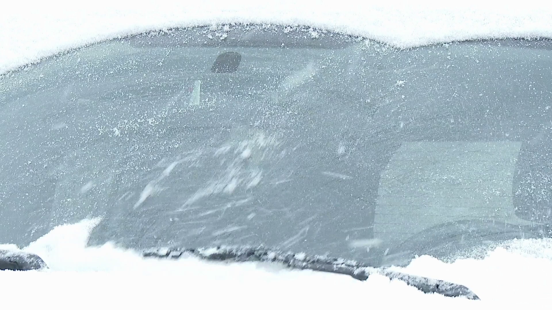 Closeup of windshield wipers brushing away the snow from a car's windshield. Stock Video