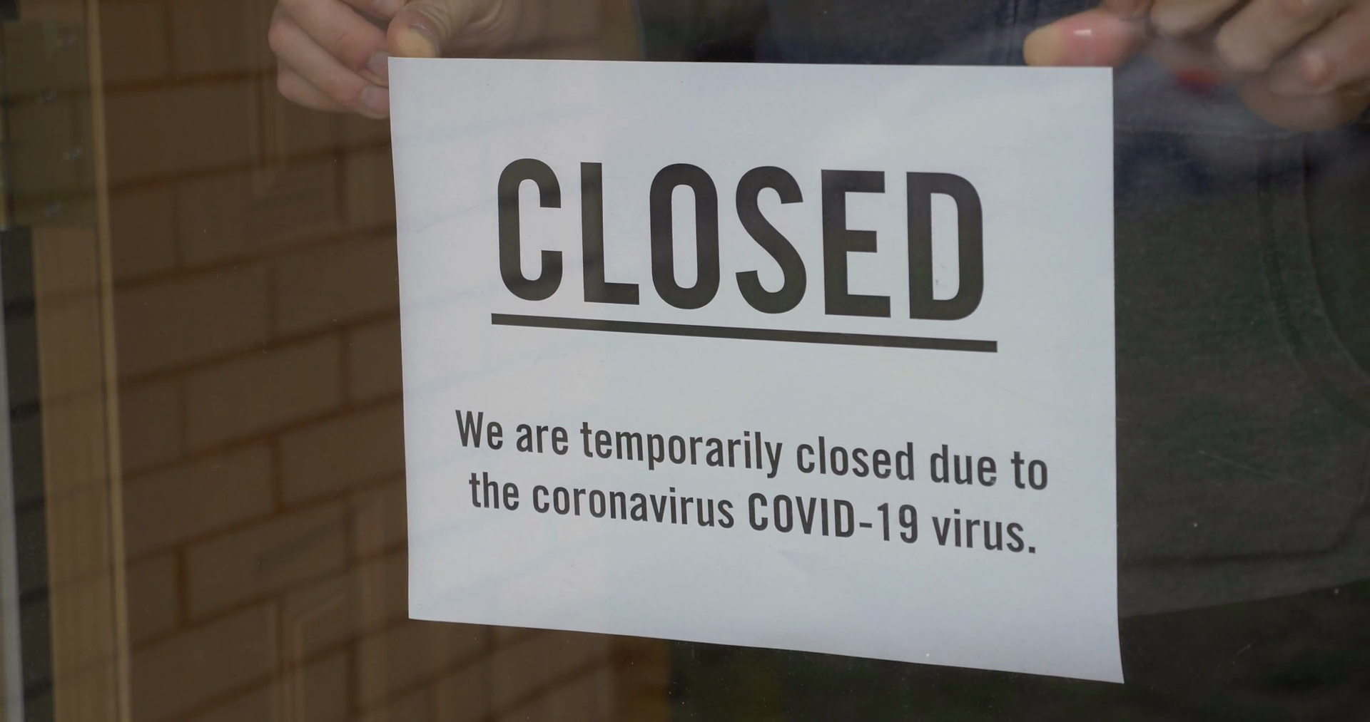 A business owner puts a CLOSED sign on the front door due to the