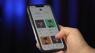 Circa November, 2021 - A user scrolls through a collection of Bored Ape Yacht Club NFTs on his mobile phone.