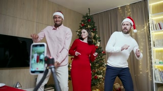 funny friends record reels stories front smartphone camera for social networks during New Year holidays party Christmas Eve celebration. Having fun dancing look pose at camera at home. live streaming