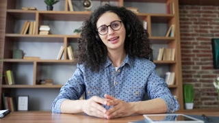 Webcam view. Confident woman in headset talking on video call looking in camera sitting in home office. Female freelancer, tutor, coach or teacher has online meeting, training, course webinar remotely