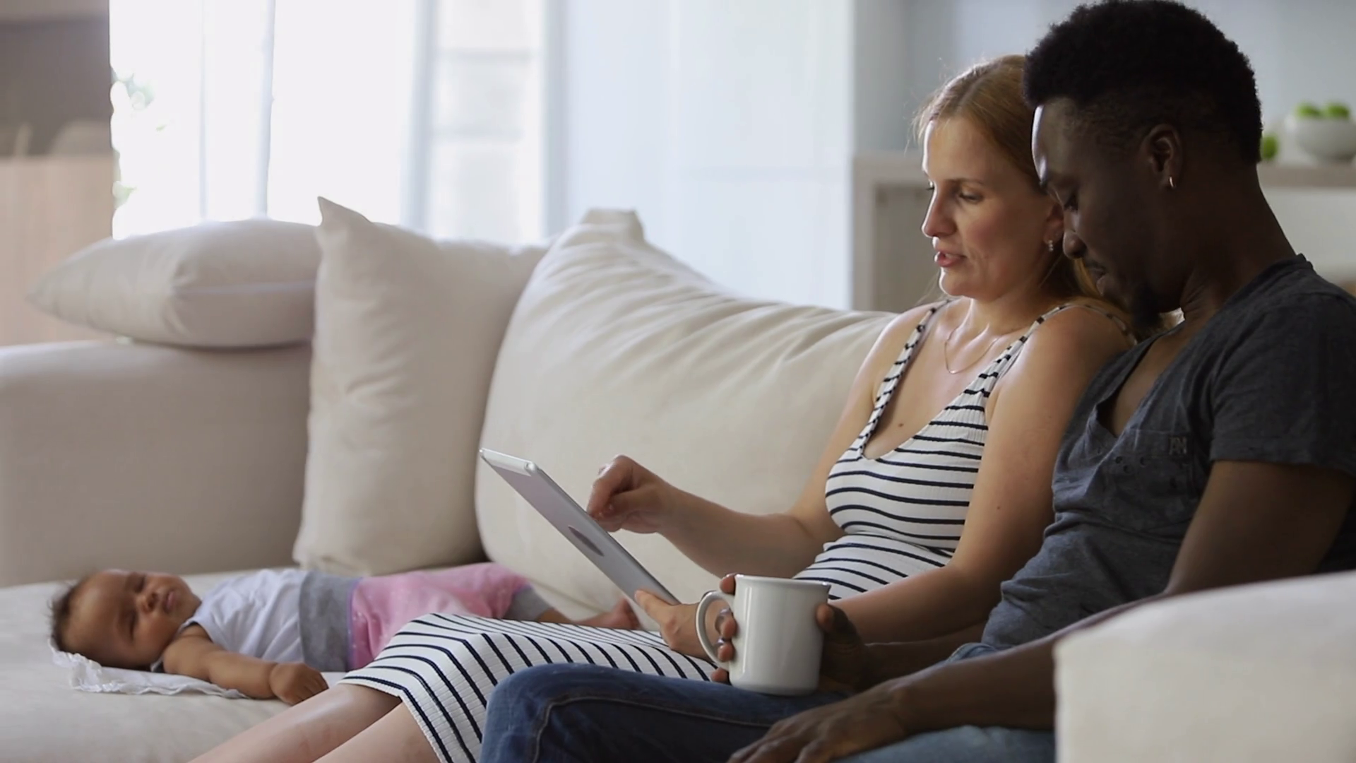 African American husband and Caucasian wife using tablet sitting on sofa at home interior spbi picture