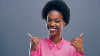 Happy woman, face and thumbs up for success, achievement and like emoji or fashion vote in studio
