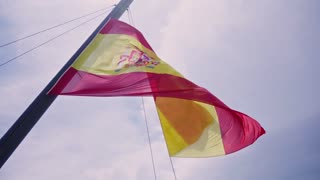 Vibrant Spanish flag waving proudly against a bright blue sky