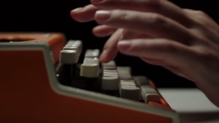 Human hands typing on retro typewriter close-up, fingers pressing buttons of old-fashioned typewriter keyboard on black background.