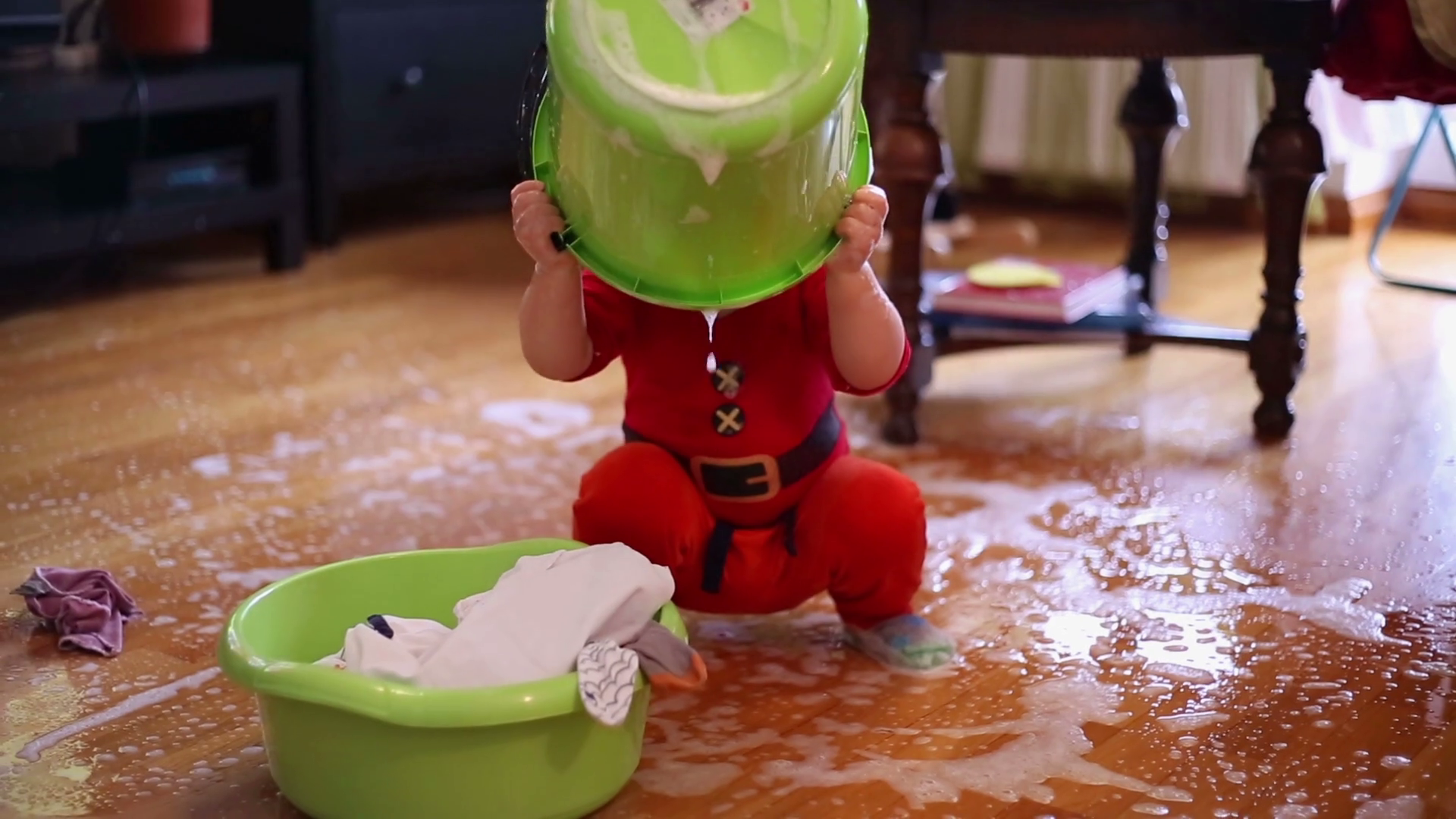 Cute baby toddler playing with spilled water on the floor at home Stock