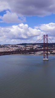 Ponte 25 de Abril Suspension Bridge and Lisbon Skyline. 25th of April Bridge. Blue Sky and Cumulus Fluffy Clouds. Portugal. Aerial Hyper Lapse, Time Lapse. Vertical Video