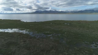 Low-Level Flying Forward over Song Kol Lake. Mountains on Background. Kyrgyzstan. Aerial View. Establishing Reveal Shot