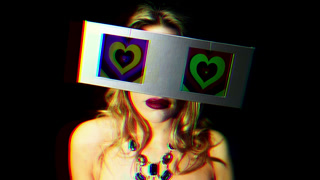 woman looking around with 2 video screens as eyes. the screens have a hypnotic video of hearts on them