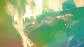 log fire burning in a fireplace in slow motion with overlayed colourful light leaks