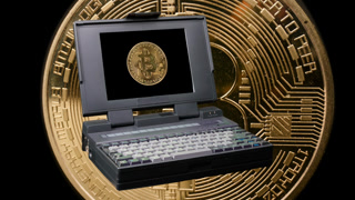 A very old vintage computer laptop spinning with a bitcoin on screen and coins in the background