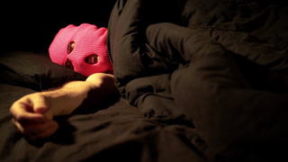 A man in anonymous mask in bed