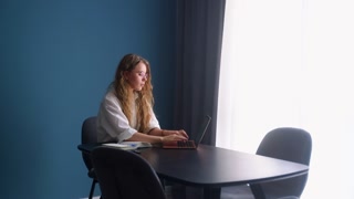 Girl doing homework at home. Female student watching online lesson at remote learning class on laptop. Woman studying, writing notes to notepad, listens to web class tutorial. Remote work with a team.
