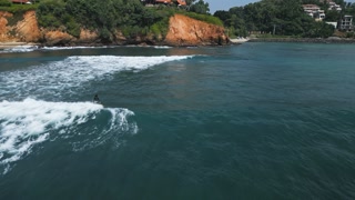 2023-01-09 - Jungle Beach, Weligama, Sri Lanka. Surfers catch waves at exotic beach, action-packed adventure. Aerial view showing water