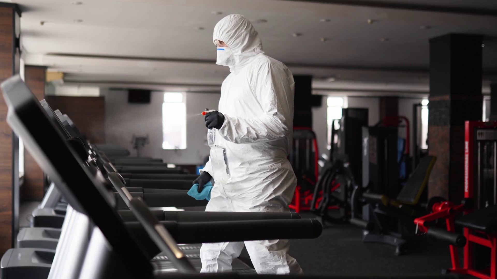 Hazmat worker disinfects gym fitness equipment from coronavirus covid19 hazard with
