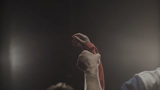 Rear view of the referee who raises the winner's hand. The referee raises the hand of the boy winner in the ring
