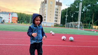 Cute Caucasian baby boy takes a ball from the ground. Kid throws the ball and then picks another one. Cute Caucasian baby boy takes a ball from the ground. Kid throws the ball and then picks another one