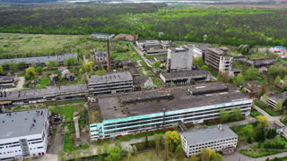 Empty apocalipse city with damaged houses. Aerial view of ruined abandoned building. An aerial view shows the scale of an abandoned industrial area on a cloudy day. Factories and large buildings are visible alongside growing trees. This video shows