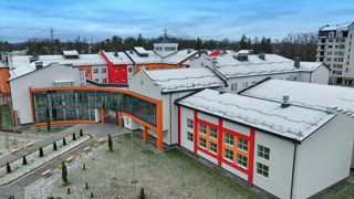 Bright exterior of a new school building. Modern architecture decisions in urban construction. Bright exterior of a new school building. Modern architecture decisions in urban construction. Trees and apartment blocks at the backdrop. Aerial footage