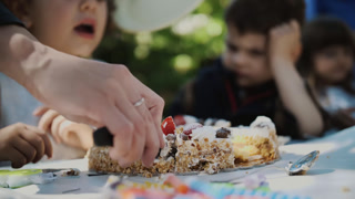 Children watching as a birthday cake is cut at a festive table. Concept of happy family moments and anniversary celebration.