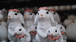 Assortment of ceramic Easter bunny statuettes on retail display. Spring holiday interior decoration and traditional market souvenir.