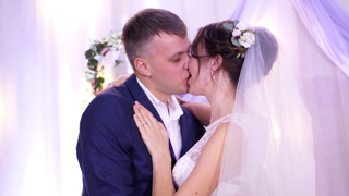 Loving newlywed couple kissing and hugging passionately during their wedding day outdoors.