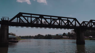 Wide view of the historic Bridge on the River Kwai crossing the Kwai Yai River in Kanchanaburi, Thailand, a famous World War II landmark connected to the Burma Railway.