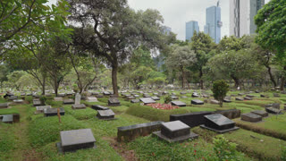 Public cemetery at Karet Bivak in Jakarta, Indonesia, showing rows of graves surrounded by trees and greenery. Calm and reflective atmosphere representing life, death, memory, and a peaceful resting place within an urban environment.