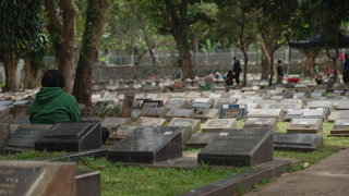 Bandung, Indonesia - March 27, 2026: Rows of graves in a Muslim cemetery with visitors present, showing burial traditions, remembrance, and religious culture in Indonesia. Calm and reflective atmosphere in a public graveyard.