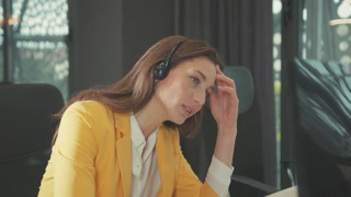 Tired woman office manager with headset providing online support video chat conference customer webinar looking at computer screen working.