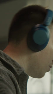 Worker wearing headphones concentrating on editing, Male professional at computer engaged in video editing task