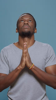Vertical video: Male model holding hands in prayer to do spiritual session, praying to God and believing in christianity. Religious adult