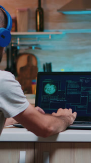 Vertical video Back view of hacker with headset attacking succesfully the government using finetech, working from home in midnight