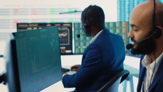 Team of forecast affiliates examining annual infographics on a big data screen, using workflow statistics at workstations. Diverse