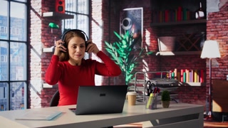 Female freelancer using ambience music on headphones to solve her tasks efficiently, working at home and with audio experience. Mature woman