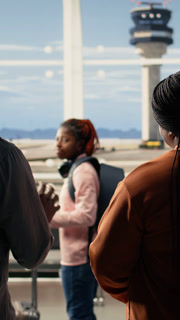 Vertical Video Sad yet proud parents waving goodbye during emotional send-off with their child at the airport. Teenager walking toward gate