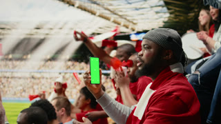 Vertical mockup screen on phone held by soccer fan in the stadium stands during world championship football match. Energetic cheering crowd