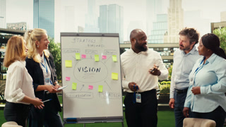 Portrait of diverse business team planning project timeline on whiteboard during outdoor presentation, informal discussion. Adding sticky
