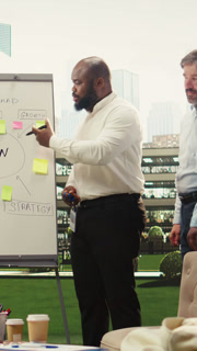 Vertical Video Portrait of diverse business team planning project timeline on whiteboard during outdoor presentation, informal discussion